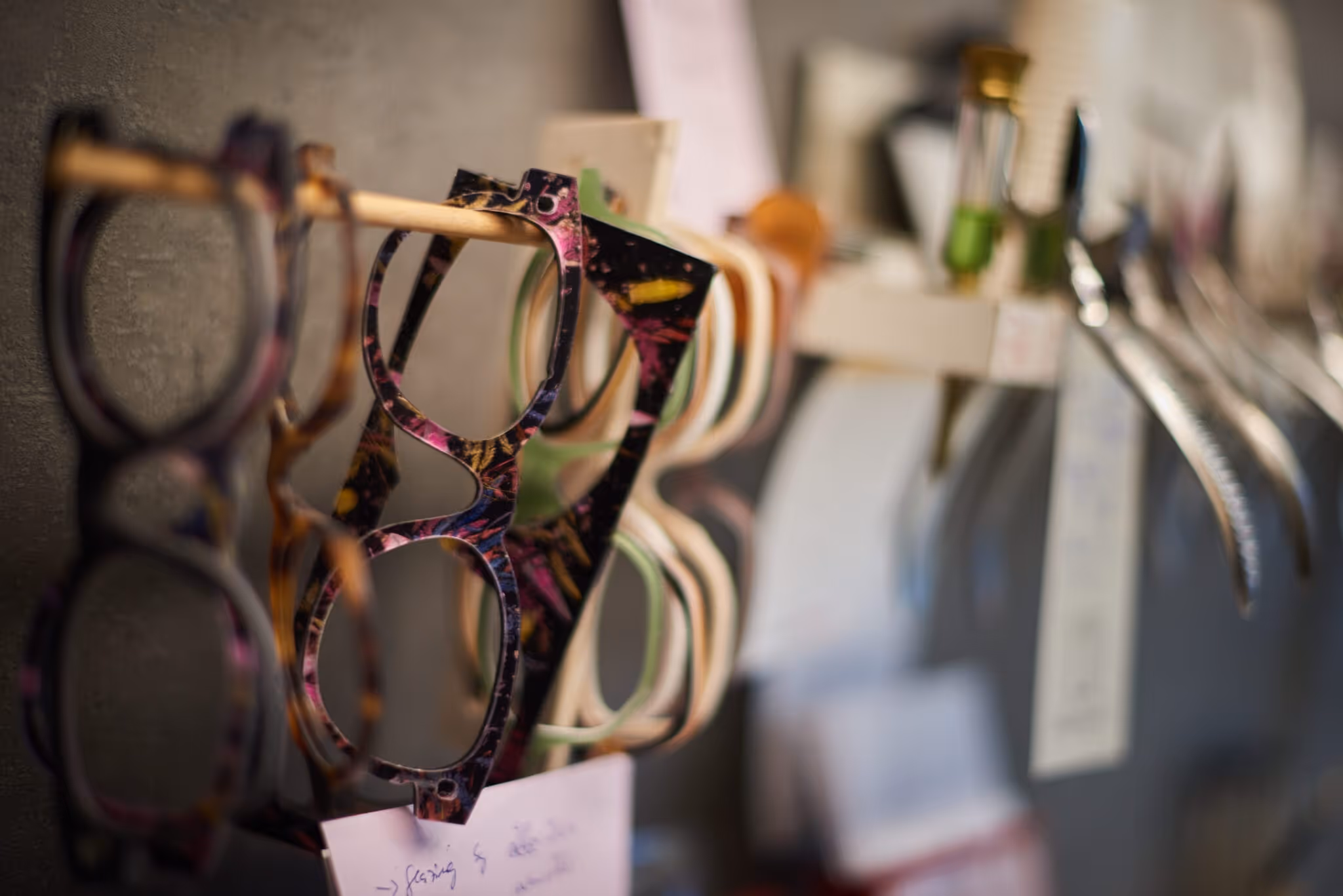 Mehrere Brillen hängen in der Werkstatt an der Wand.