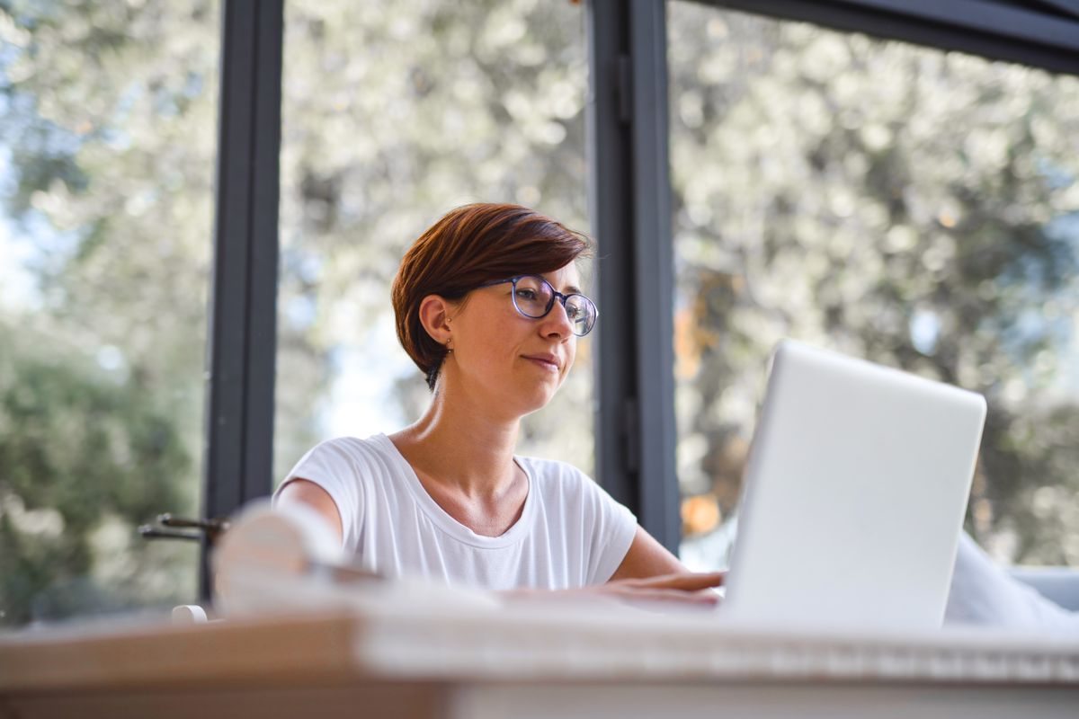 Freelancer at a laptop by a window comparing tax regimes in Poland