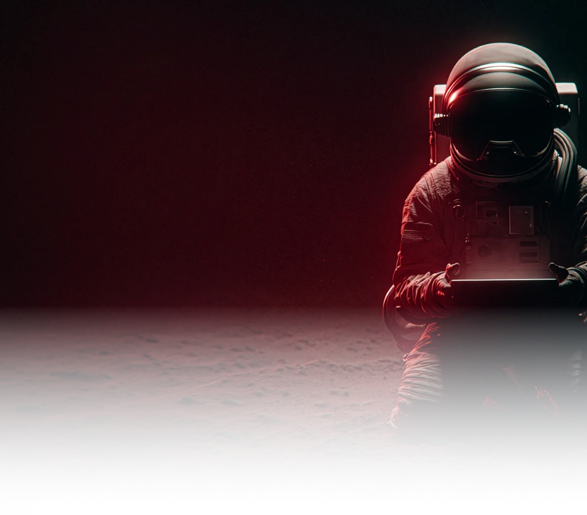 Astronaut kneeling on a dark, rocky surface, holding a glowing tablet emitting red light.