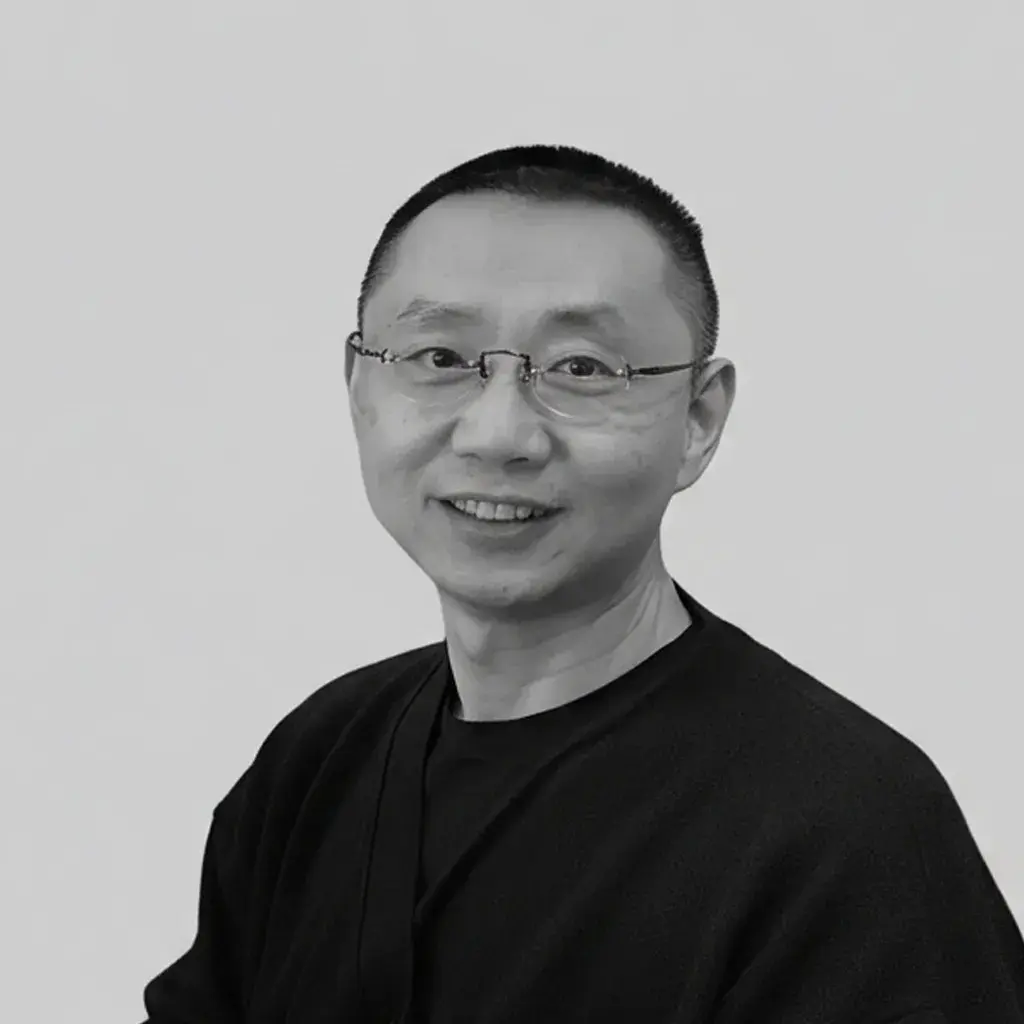 A man wearing glasses standing in front of a window