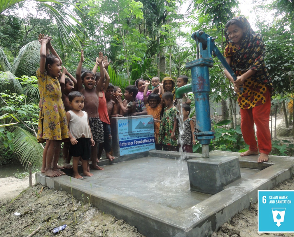 A girl pumps water from a blue hand pump well while a group of children cheer nearby in a lush green rural area.