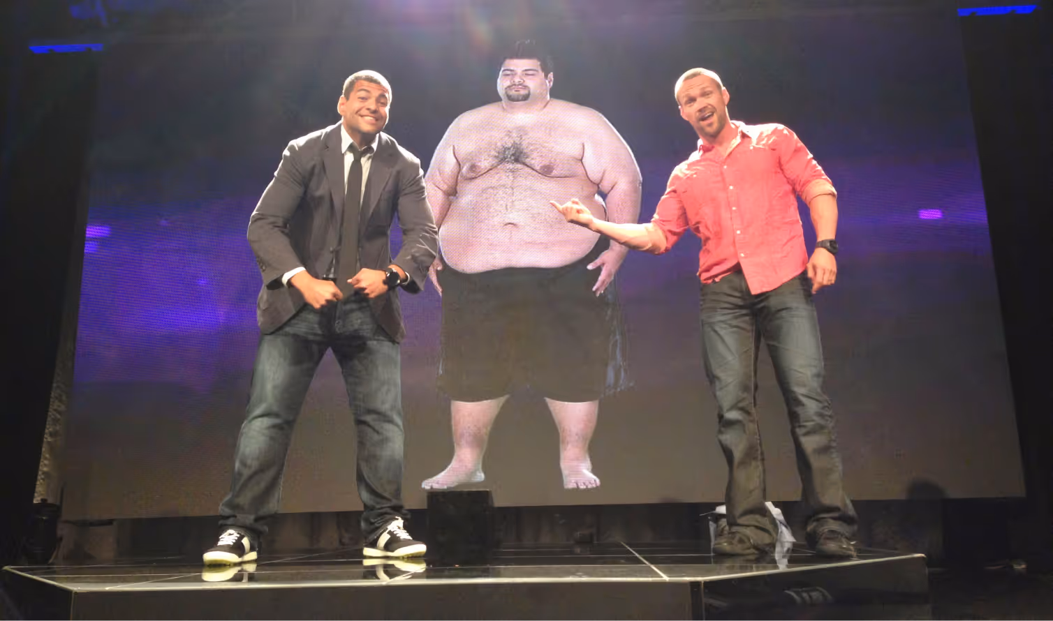 Group of people on a beach holding signs that read 'WE ♥ NOXYM', smiling and posing together.