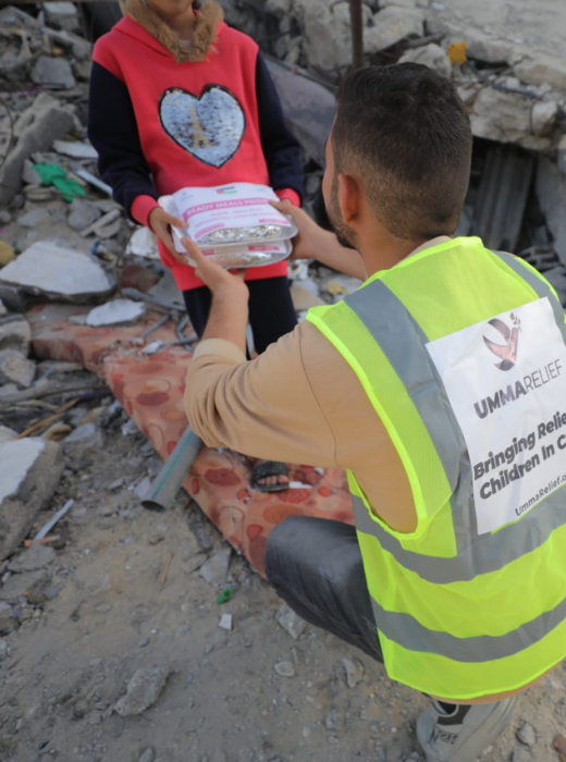 Umma Relief volunteer offering a hot meal to a child in a war-torn region, delivering care and comfort in the midst of conflict.