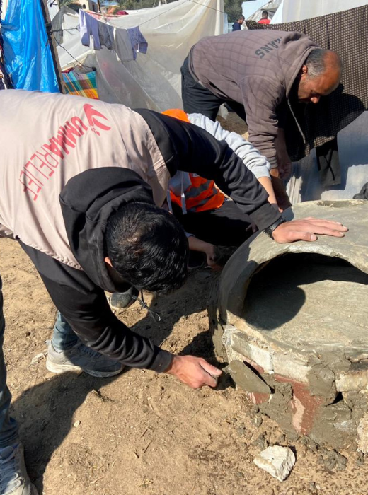 Umma Relief volunteer constructing clay ovens in a refugee camp to promote self-sufficiency and sustainable cooking solutions.