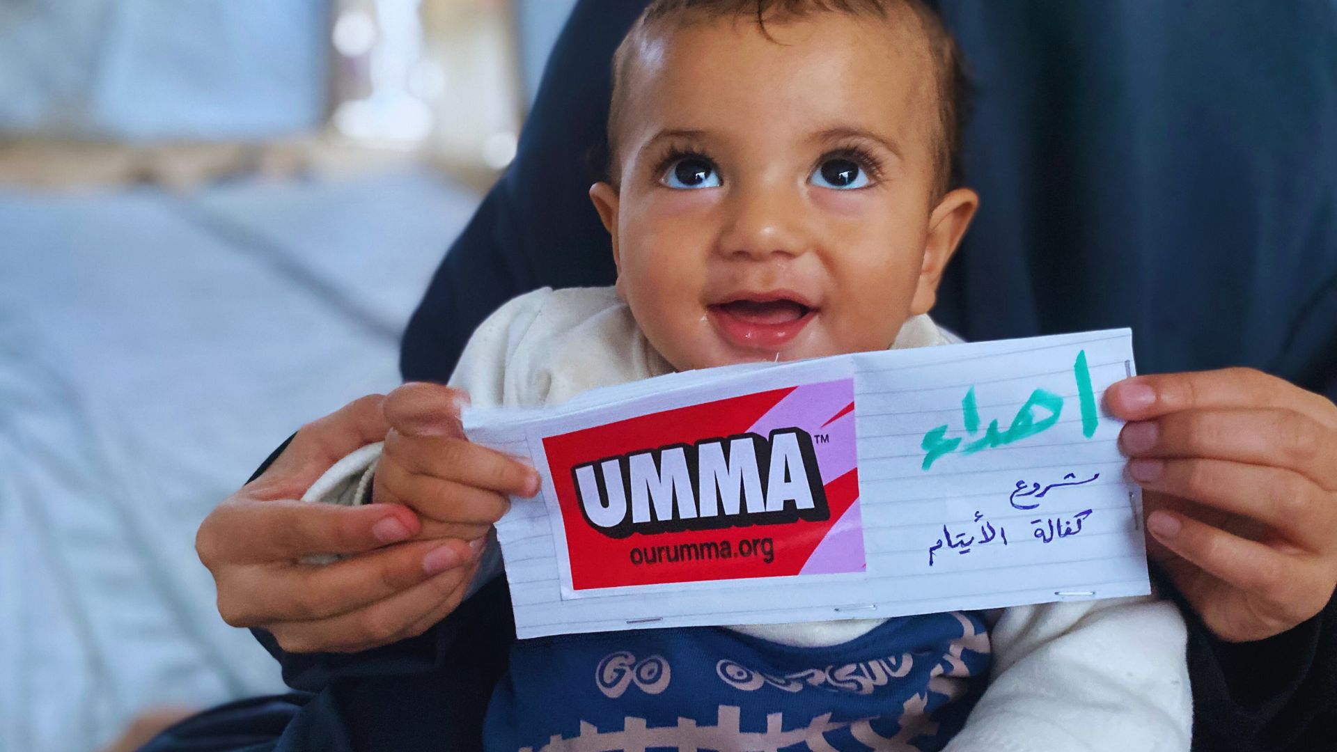 Smiling baby with Umma Foundation card