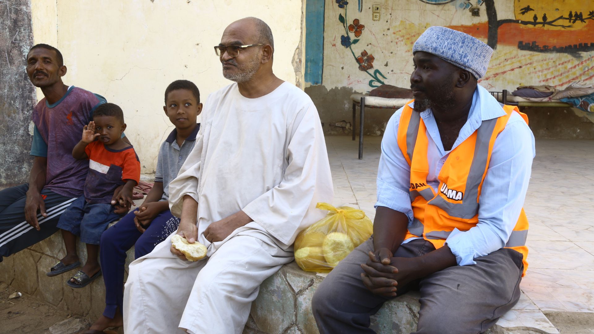 Umma aid worker with Sudanese family receiving bread.
