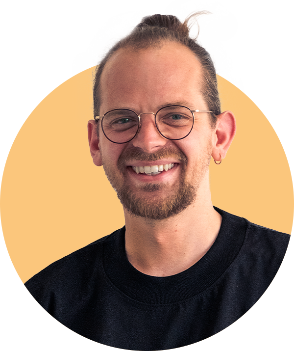 Porträt von Andi, lächelnd vor neutralem Hintergrund.