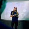 Jeune femme debout faisant une présentation devant un écran projeté flou.