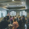 Groupe de personnes assises en cercle dans une salle lumineuse, participant à une discussion ou à un atelier.