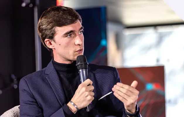 Homme parlant dans un microphone lors d'une discussion ou interview en intérieur.