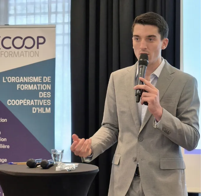 Un homme en costume bleu tenant un microphone et parlant lors d'une interview ou d'une discussion.
