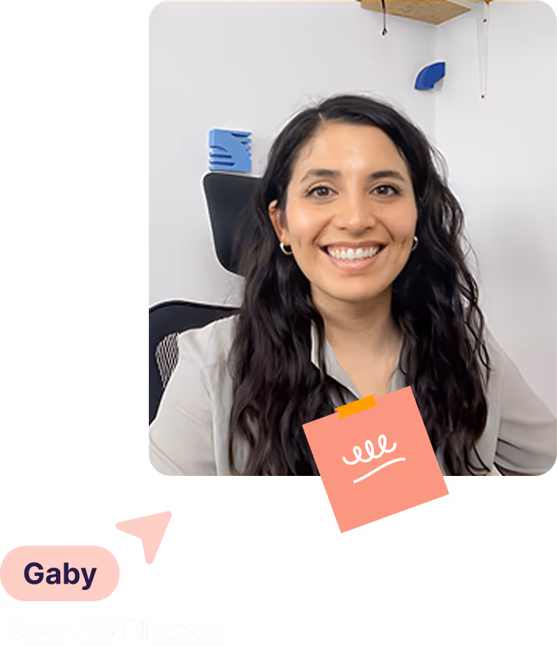 Smiling woman with long dark hair sitting in an office chair with a white wall background.