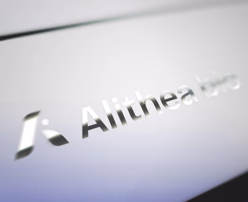 Reflective metallic text spelling 'Alithea' on a smooth surface.