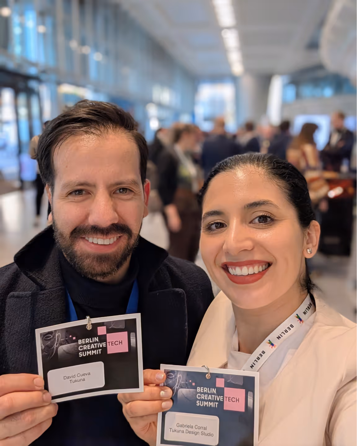 Smiling man and woman holding Berlin Creative Tech Summit name badges in a conference setting.