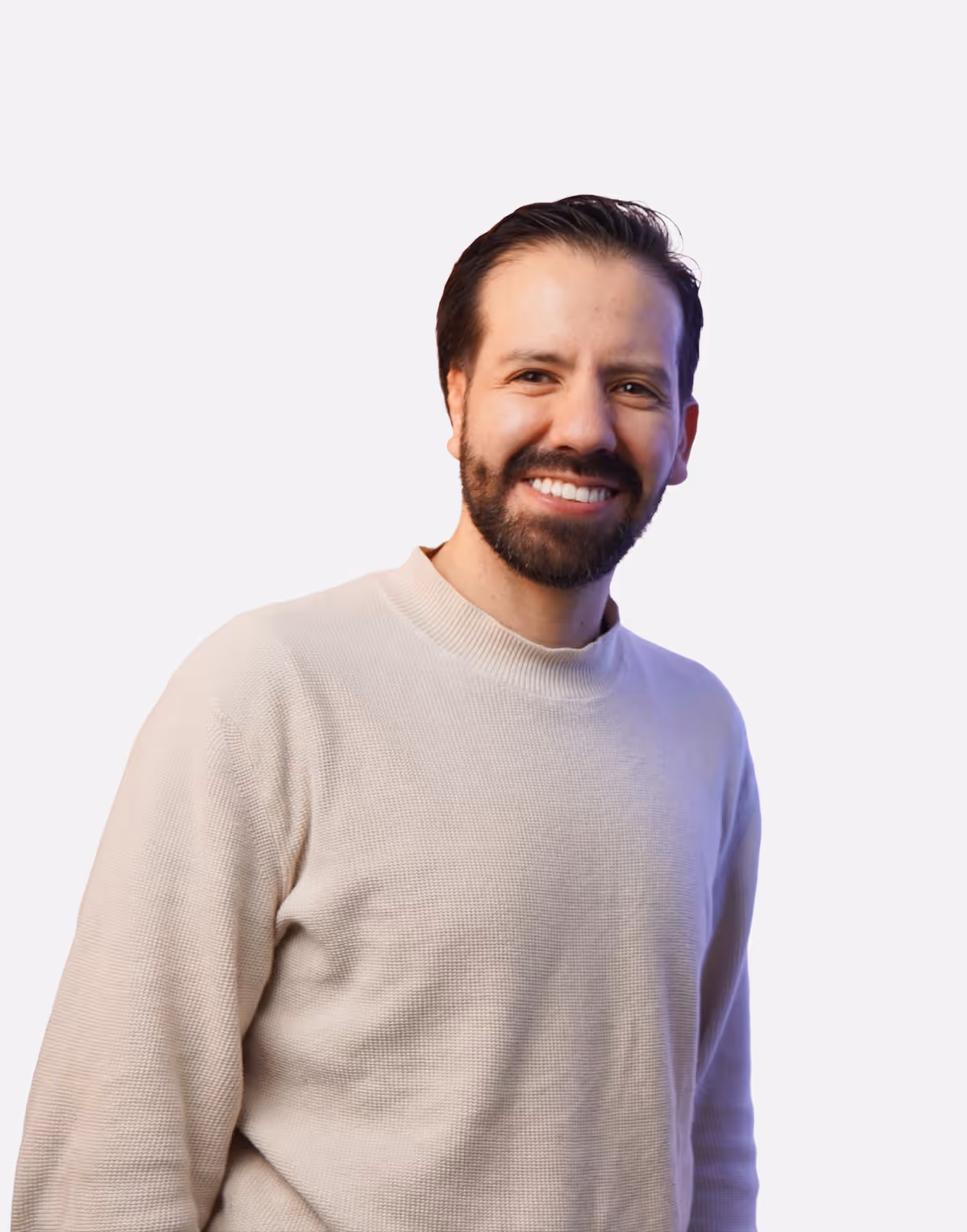 Smiling man with dark hair and beard wearing a light beige sweater against a white background.
