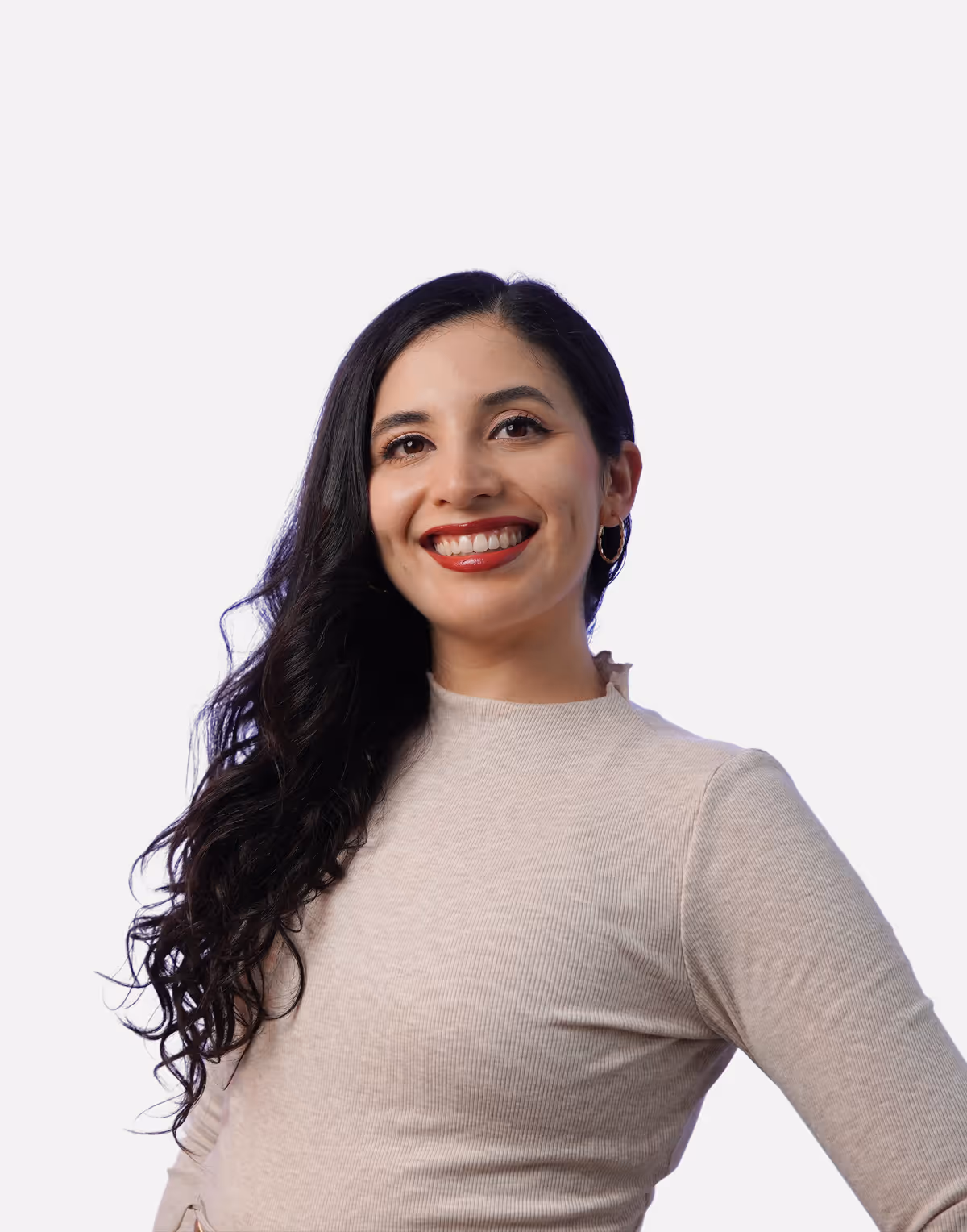 Smiling woman with long curly dark hair wearing a beige ribbed top and hoop earrings against a white background.