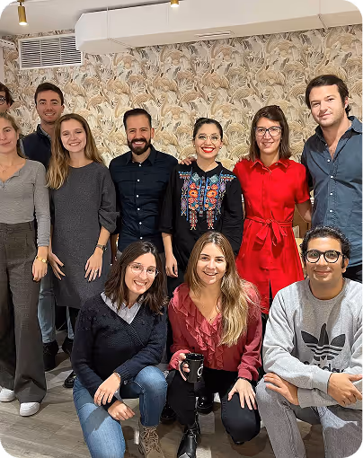 Group of ten diverse young adults smiling and posing indoors against a floral wallpaper.
