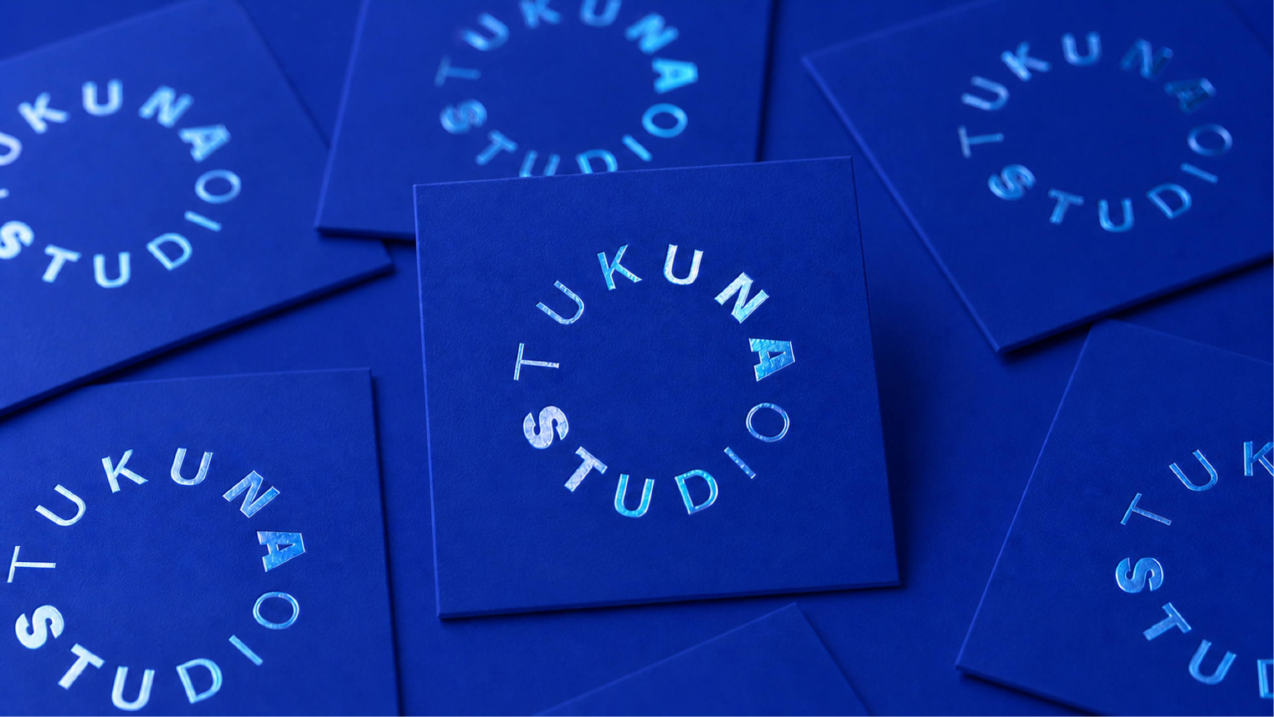 Blue cards with circular Tukuna Studio text in reflective foil on each card.