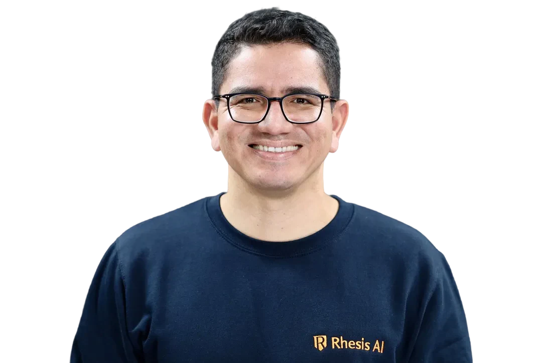 Smiling man with glasses wearing a dark blue sweater against a white background. Harry Cruz Rhesis