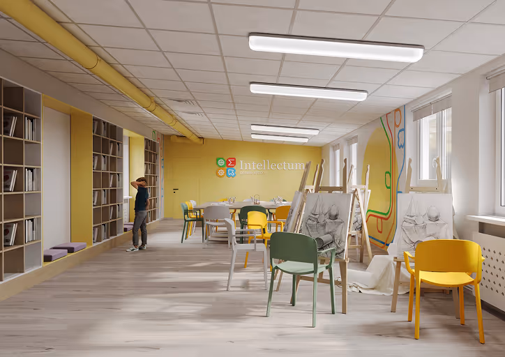 Bright classroom at Intellectum private school with easels holding sketches, colorful chairs, bookshelves, and a child looking out the window.