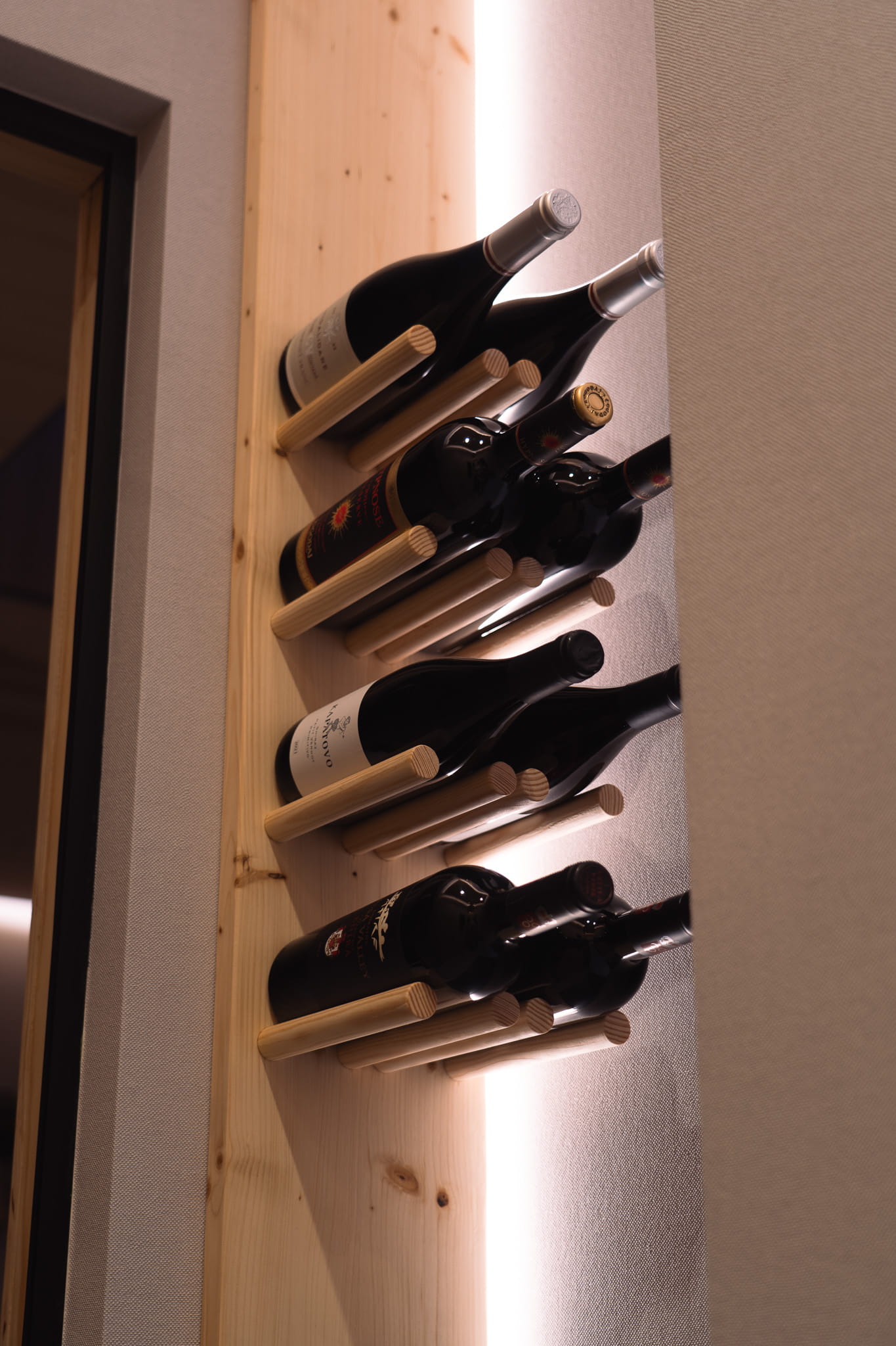 Contemporary wooden wine rack mounted on wall holding eight bottles of wine.