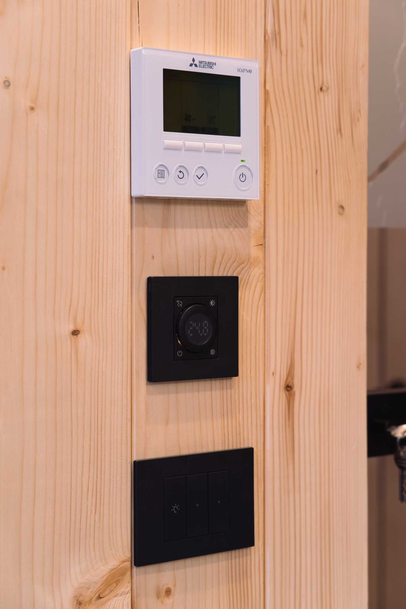 Modern wooden wine rack mounted on wall holding four bottles of wine with light behind.