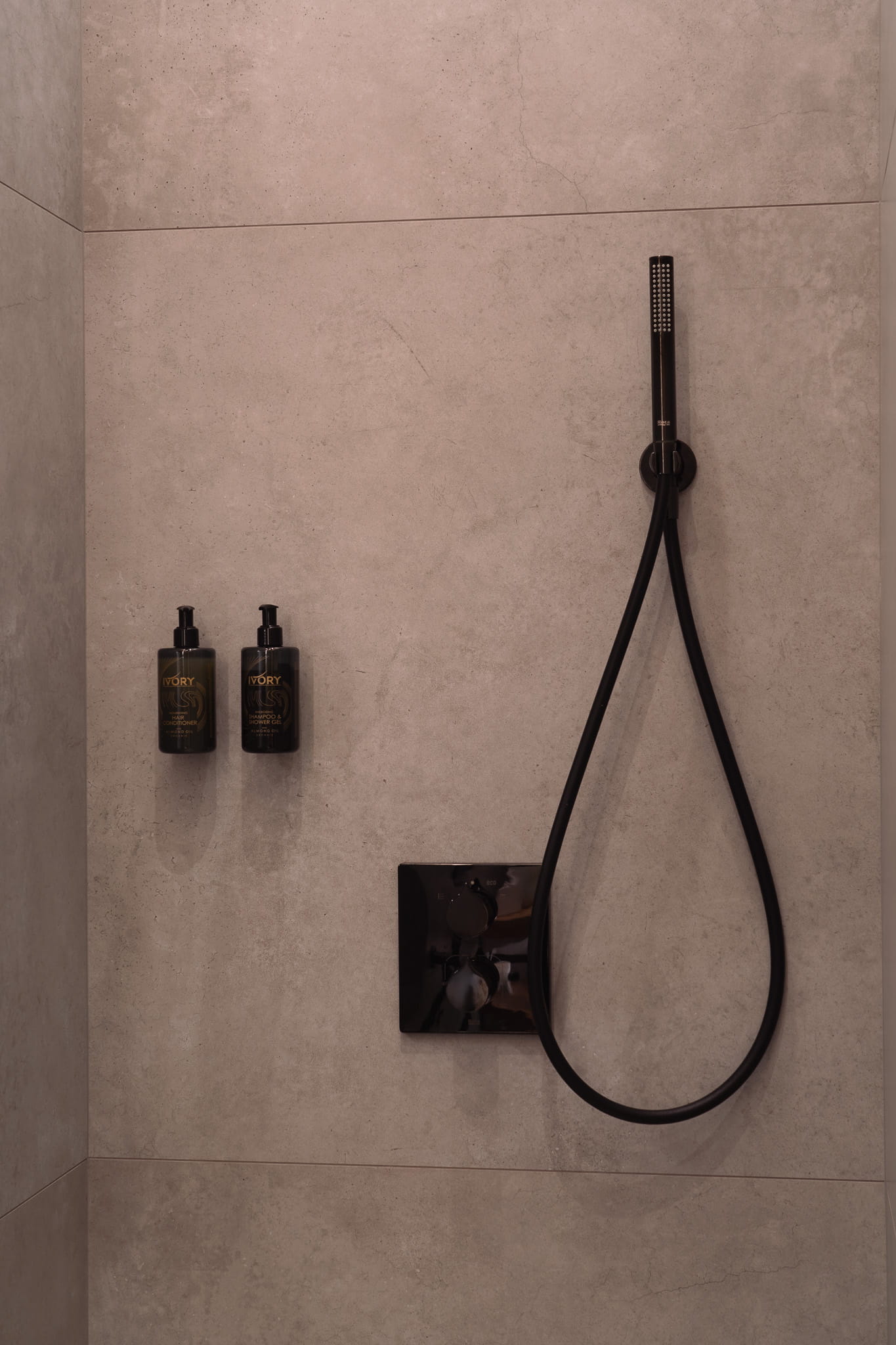 A detail photo of a shower including wall mounted shampoo and condititioner