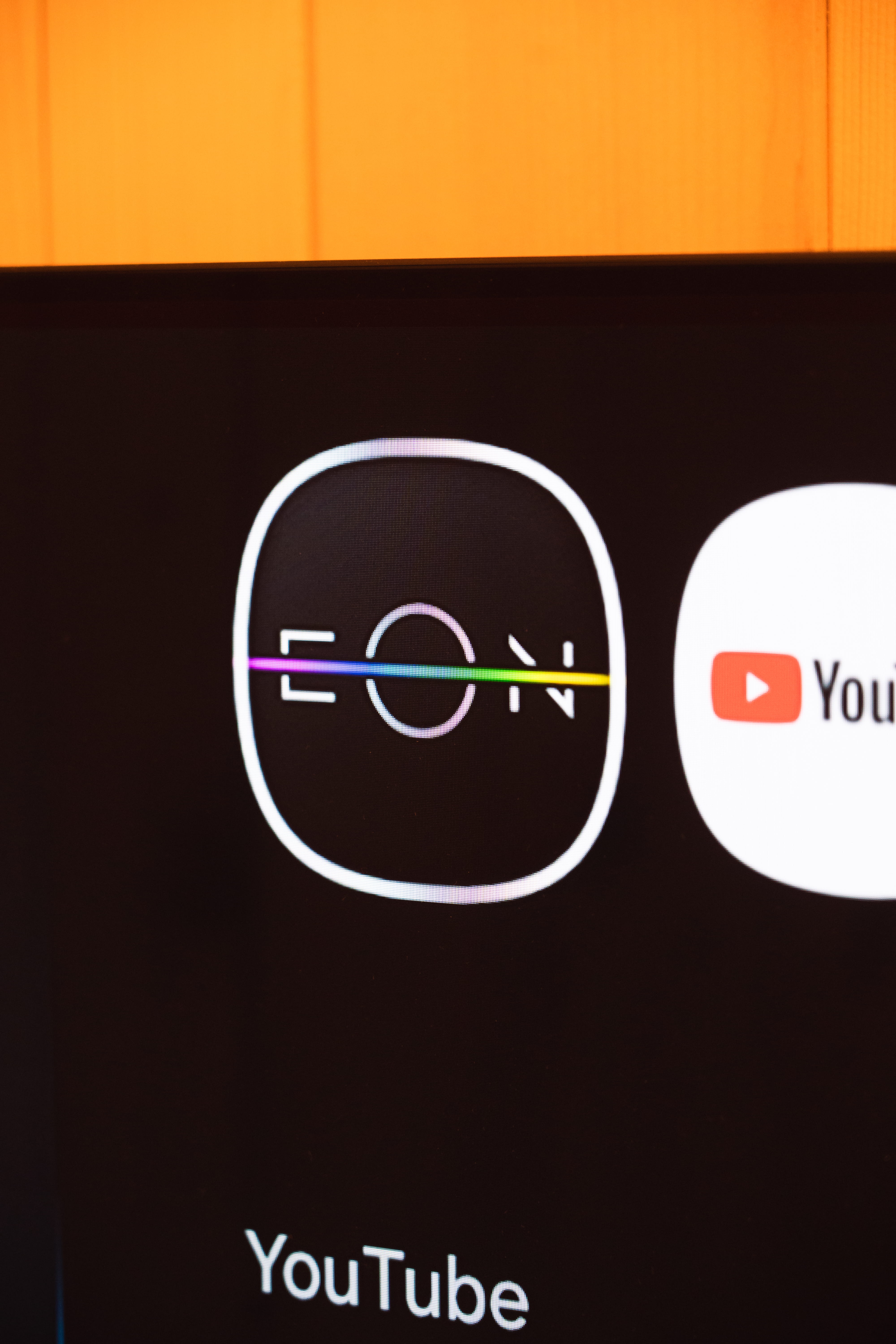 Икона с надпис EON с цветна линия през средата на тъмен фон на екран.
