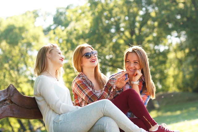 A group of three happy female friends enjoying sunshine and a good conversation made even better with the Salt app. 