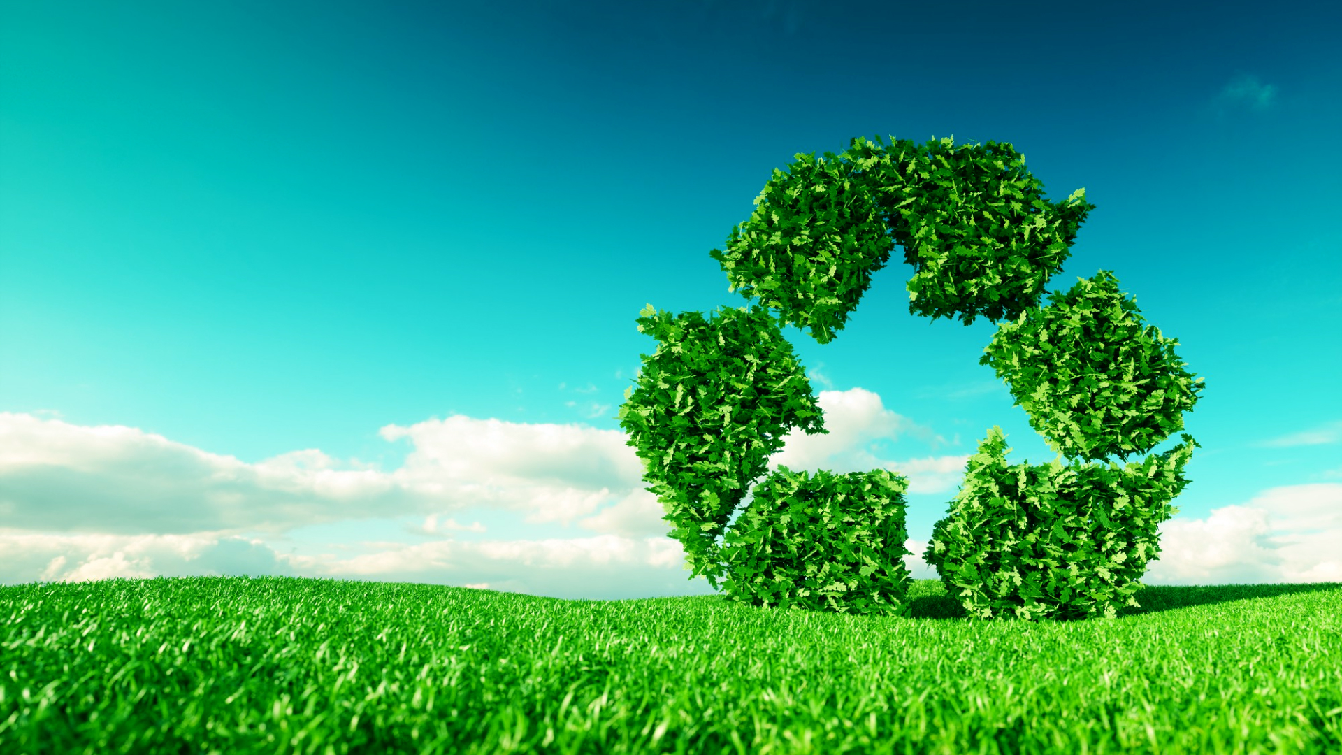 Recycling symbol made of green leaves floating above a grassy field under a blue sky with clouds.