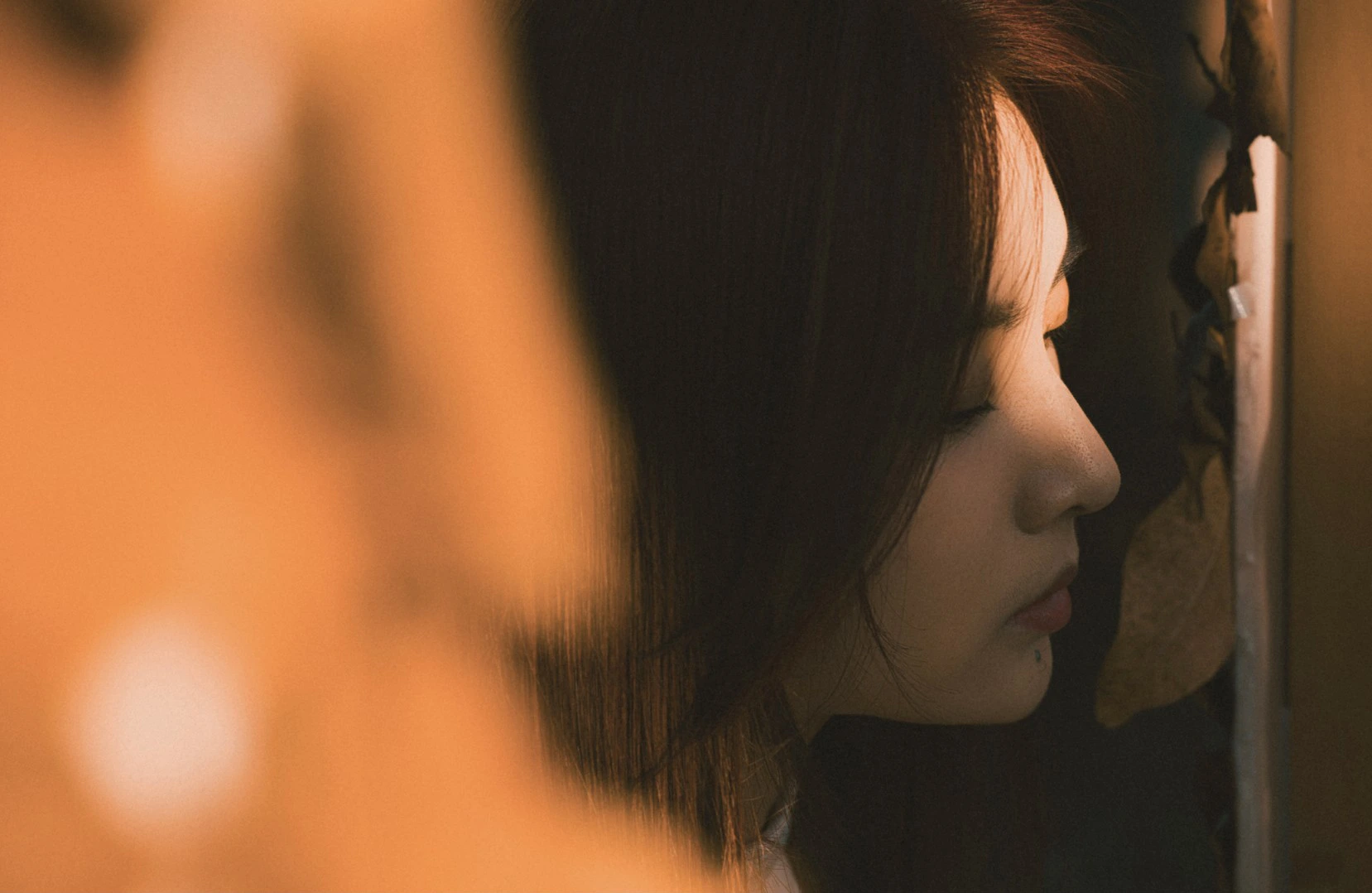 Close-up side profile of a woman with closed eyes, soft lighting highlighting her face.