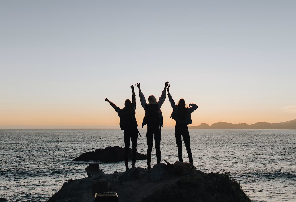 Silhouettes of women celebrating emotional safety while watching a sunrise at a CT beach