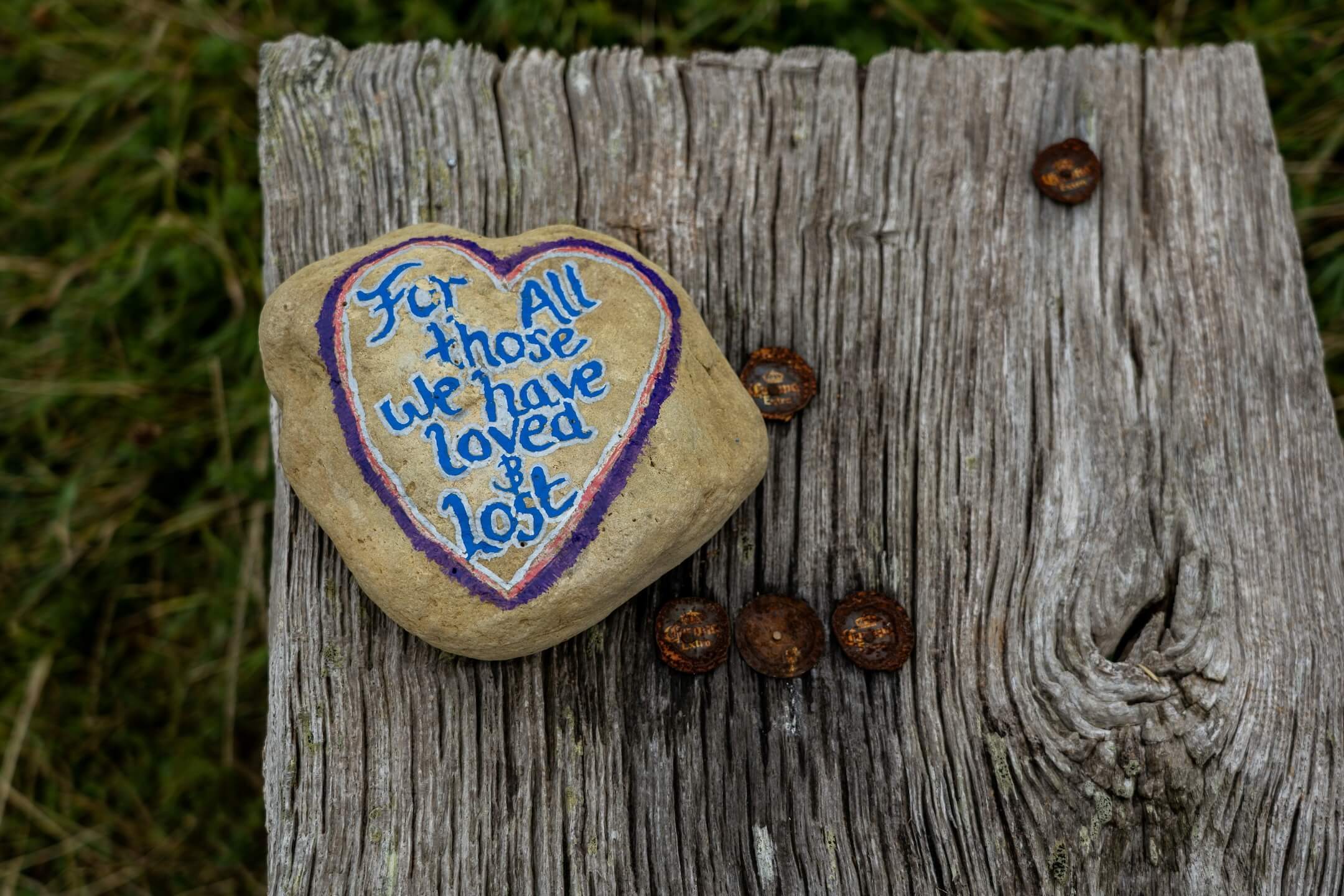 Memorial stone painted with a heart and the words “For all those we have loved and lost,” symbolizing grief, loss, remembrance, and healing.