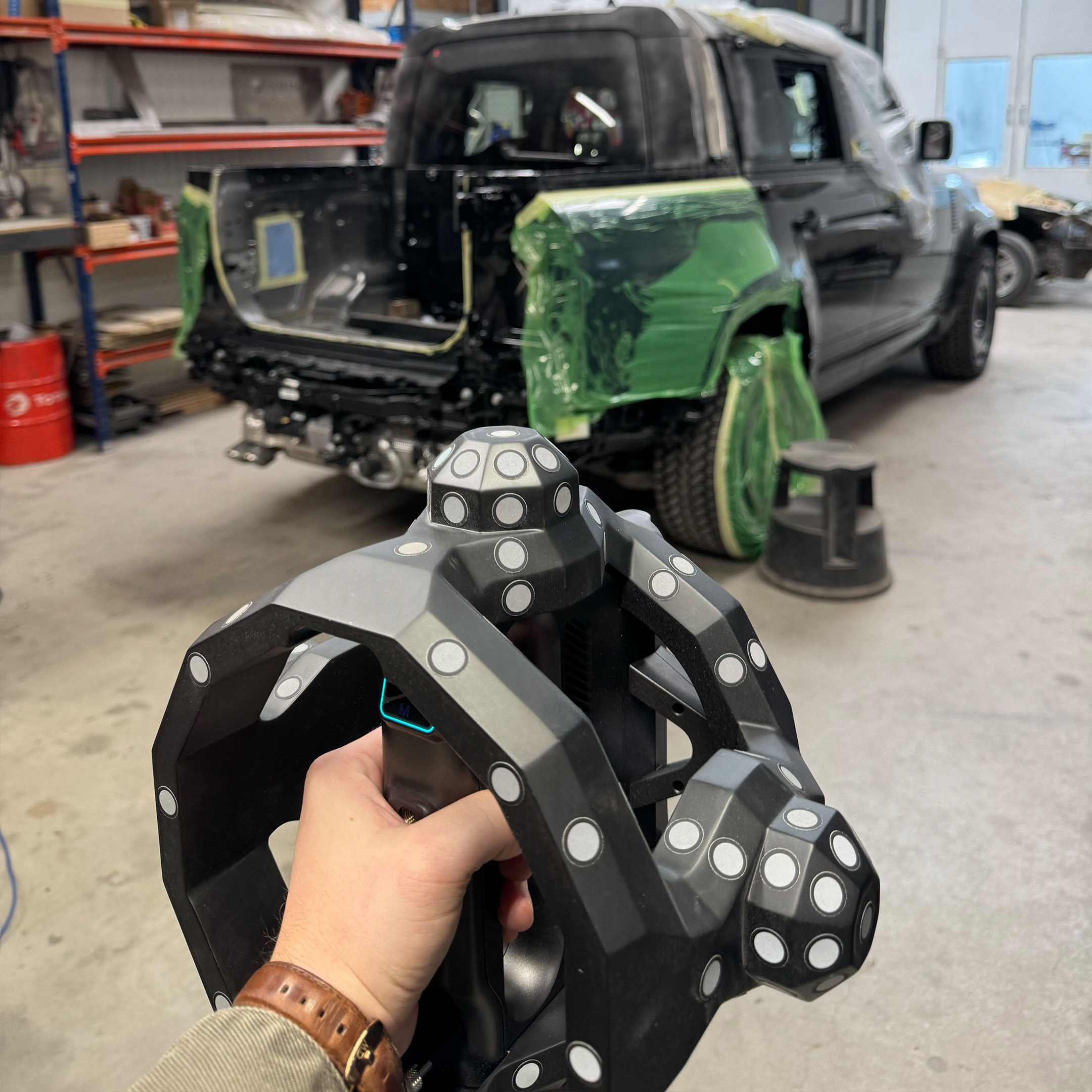 The tracking scanner head held in hand, with the Defender behind it