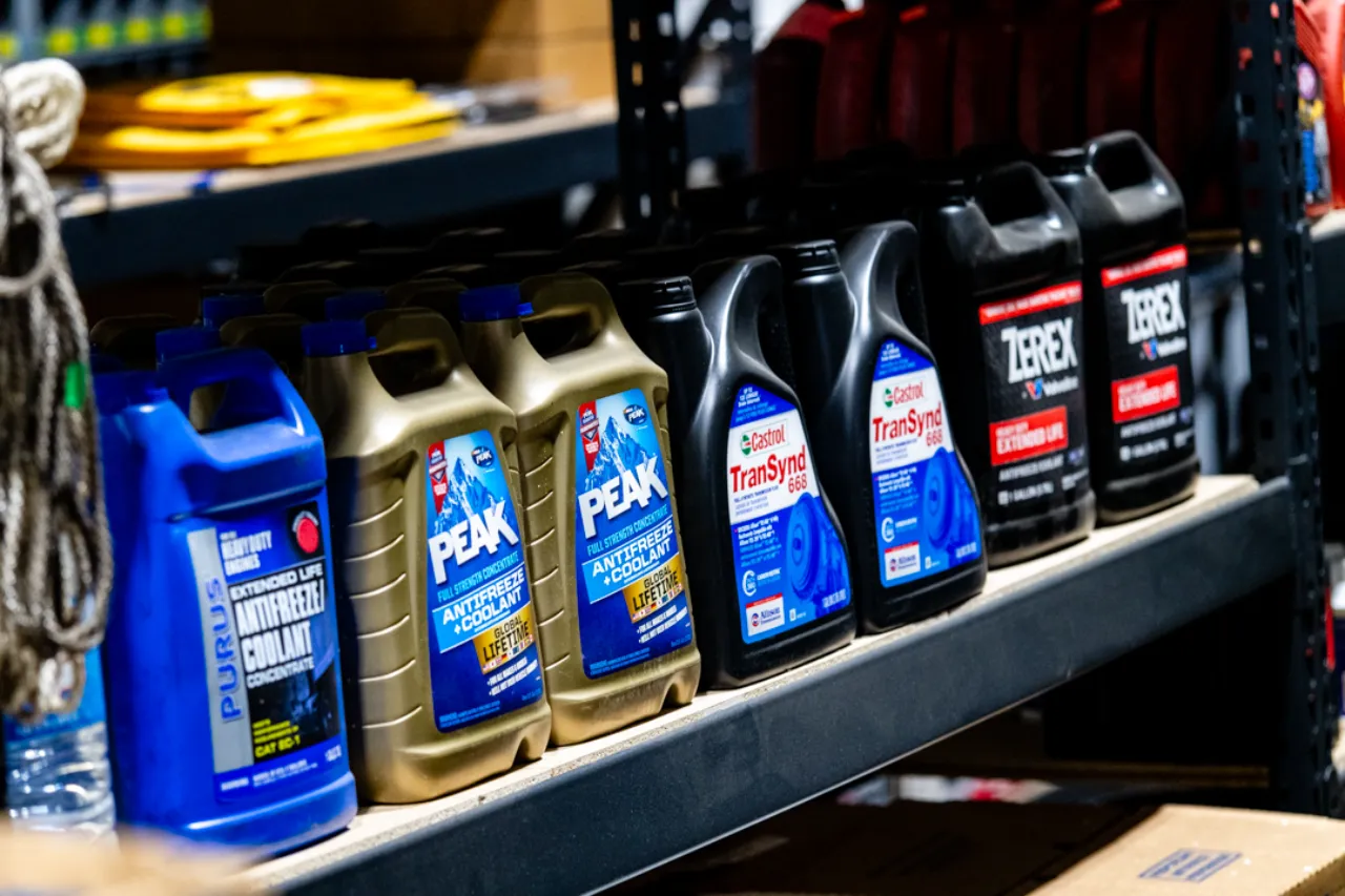 Coolant and fluids labeled PEAK, TranSynd, and Terex line repair shop shelves for heavy-duty truck service.