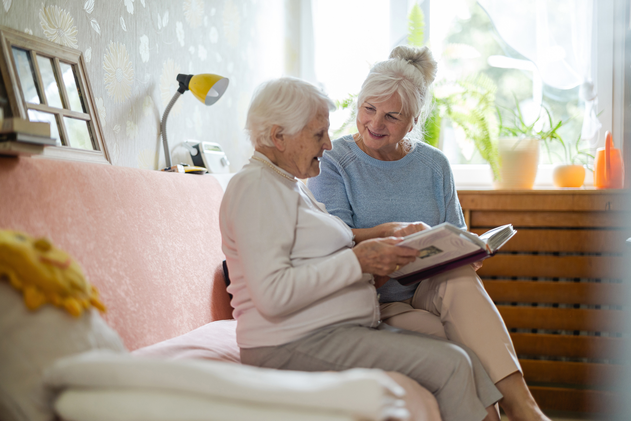 Senior woman and her adult daughter looking at a photo album together in a memory care community