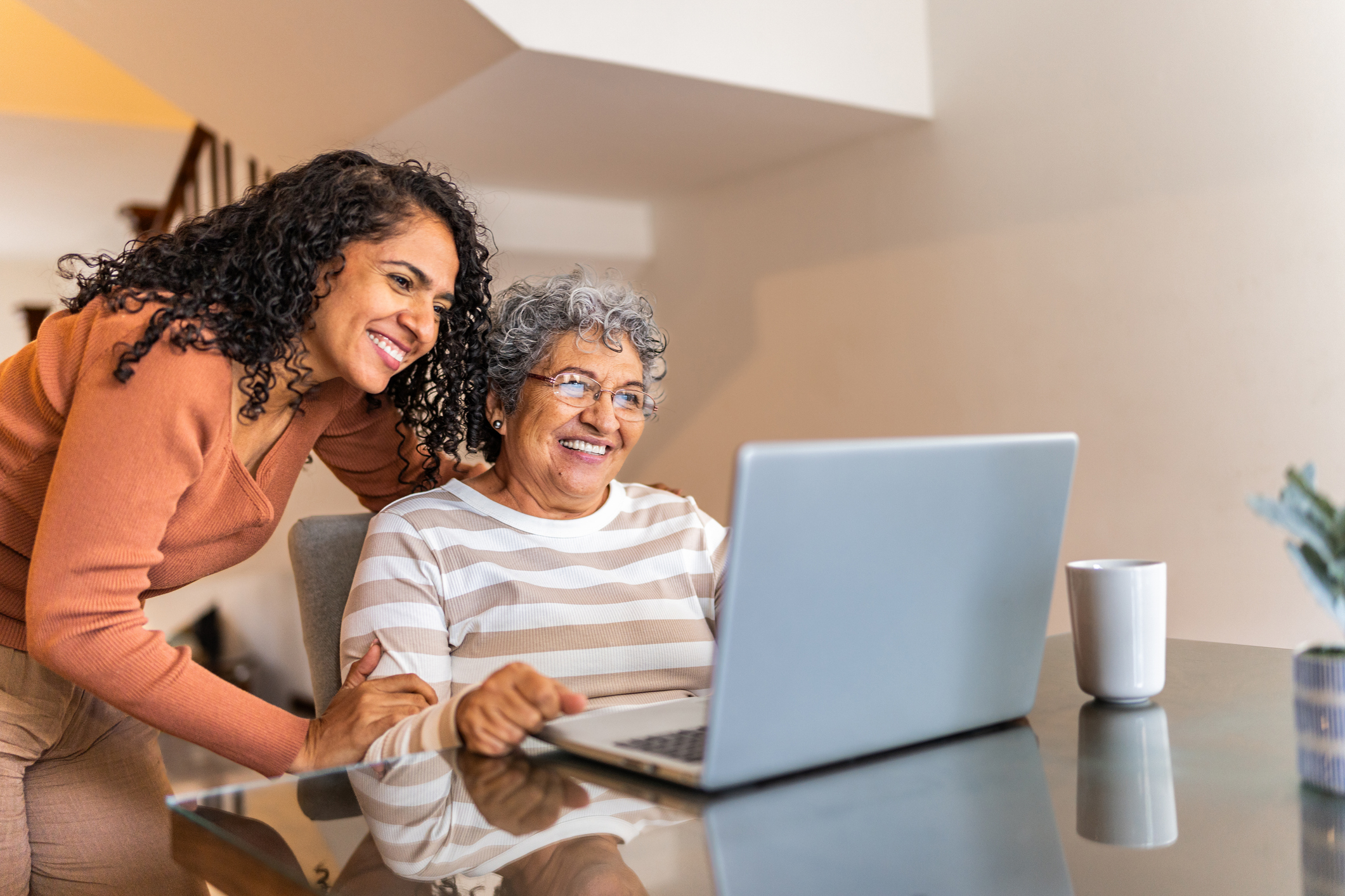 Adult daughter helping senior mother research assisted living community websites at home