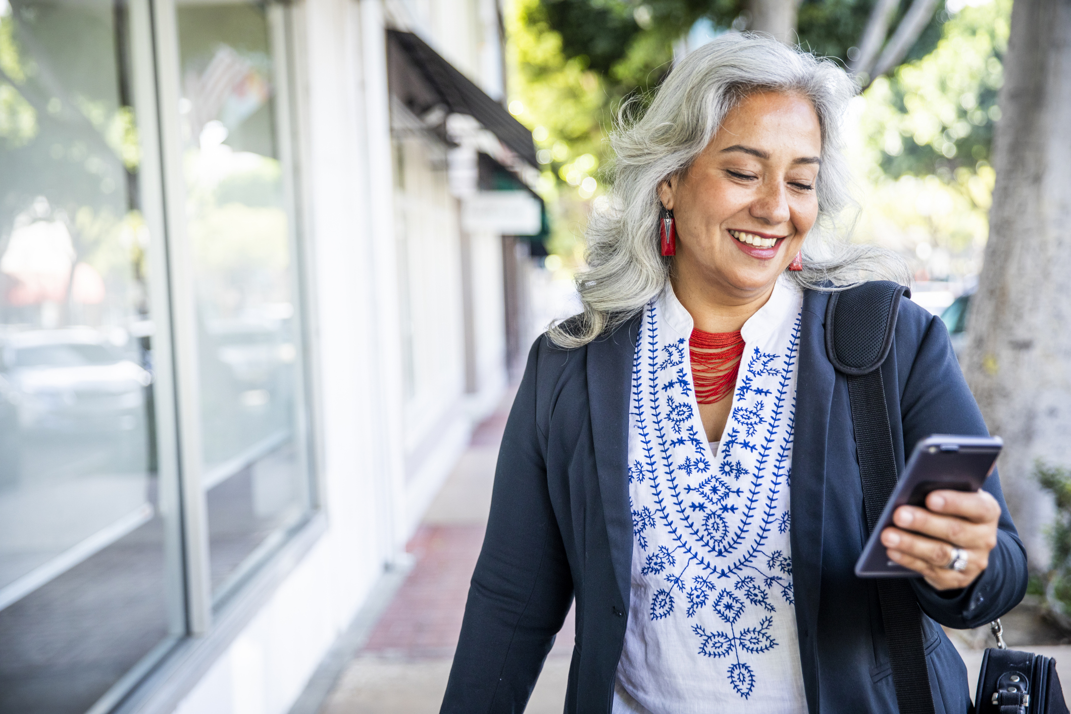 Adult caregiver smiling while researching assisted living communities on smartphone while on the go
