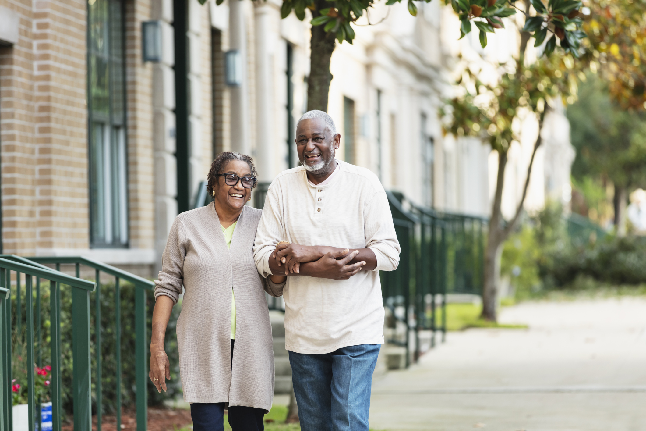 Happy senior couple walking together near their assisted living community in a welcoming neighborhood
