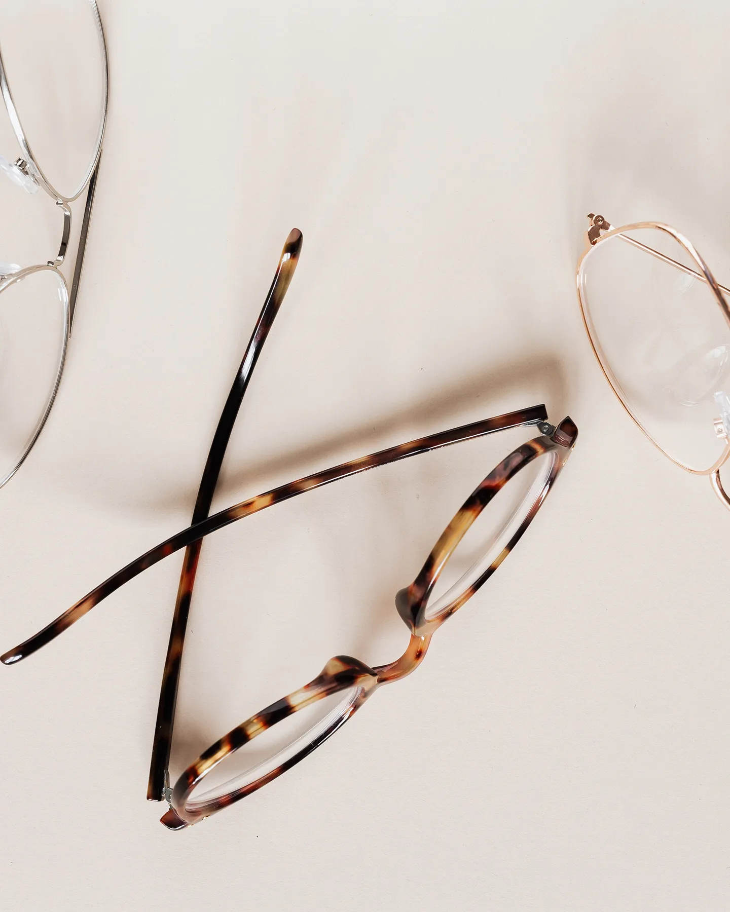 Three pairs of stylish eyeglasses in different frames on neutral background