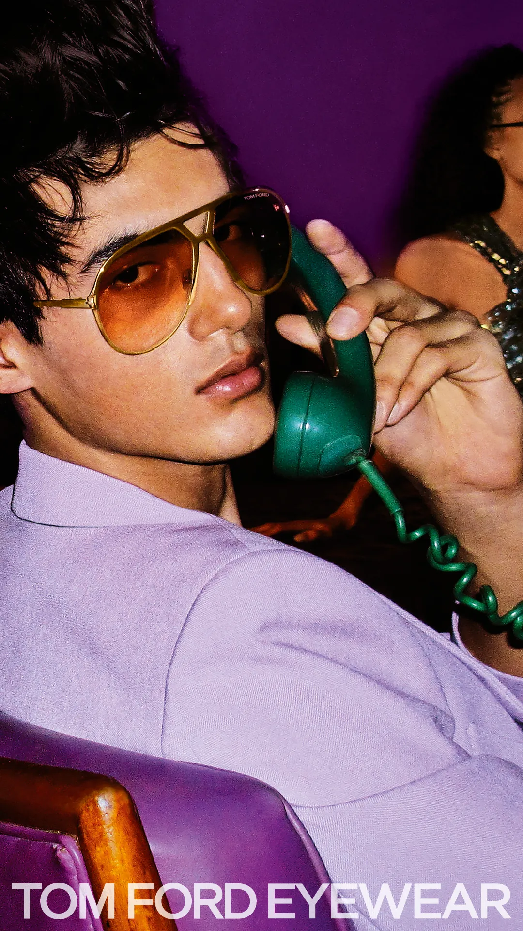 Model in yellow sunglasses talking on green vintage telephone