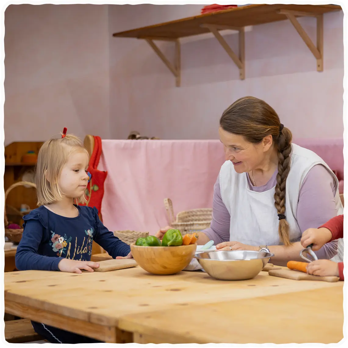 Otrok in vzgojiteljica med pripravo hrane.