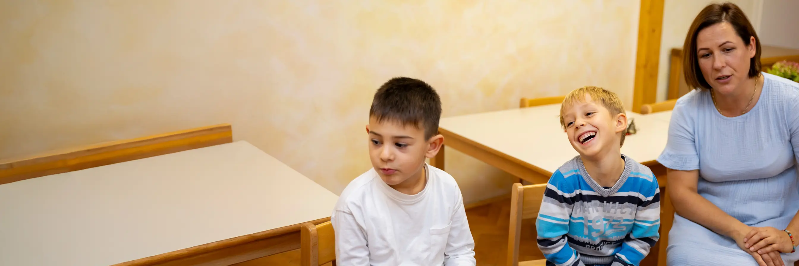 Otroci in vzgojiteljica, ki se skupaj smejijo.