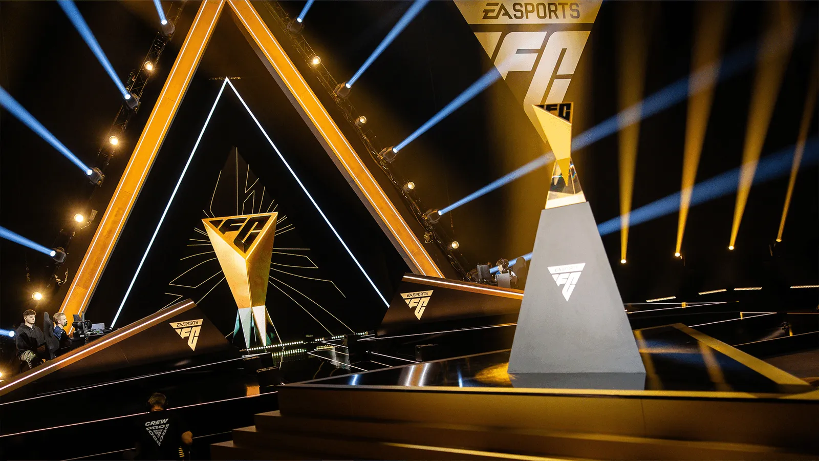 Stage setup with large triangular light structures and an EA Sports FC trophy at an esports event.