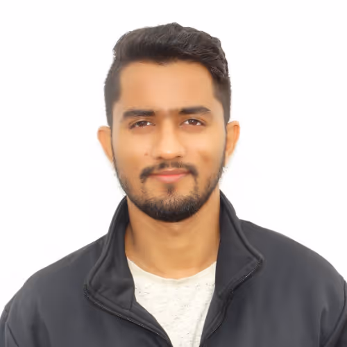 Portrait of a young man with short dark hair and beard wearing a black jacket and white shirt against a white background.