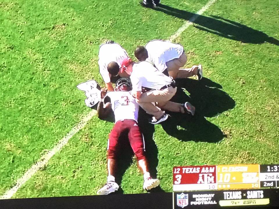 Football player lying on the grass with medical staff attending to him during a college game between Texas A&M and Ole Miss.