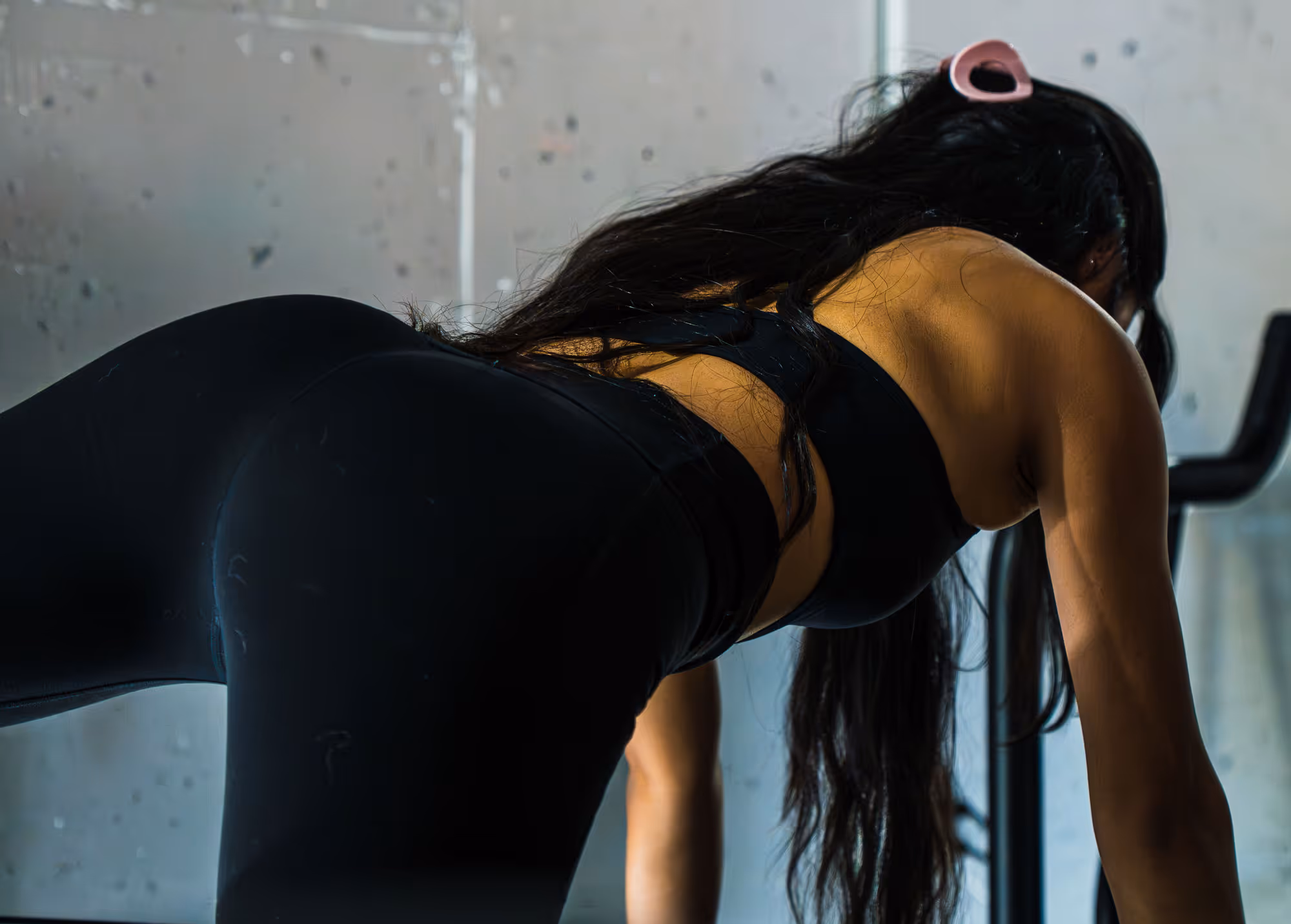 Woman in black workout clothes with long hair on the Megaformer.