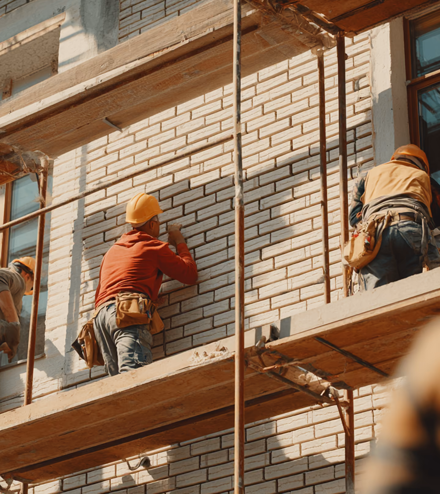 Craftsmen on scaffolding precisely pointing a brick facade for a renovation project in the Benelux.