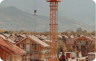 Construction site with several houses under building and a large crane in a mountainous area.