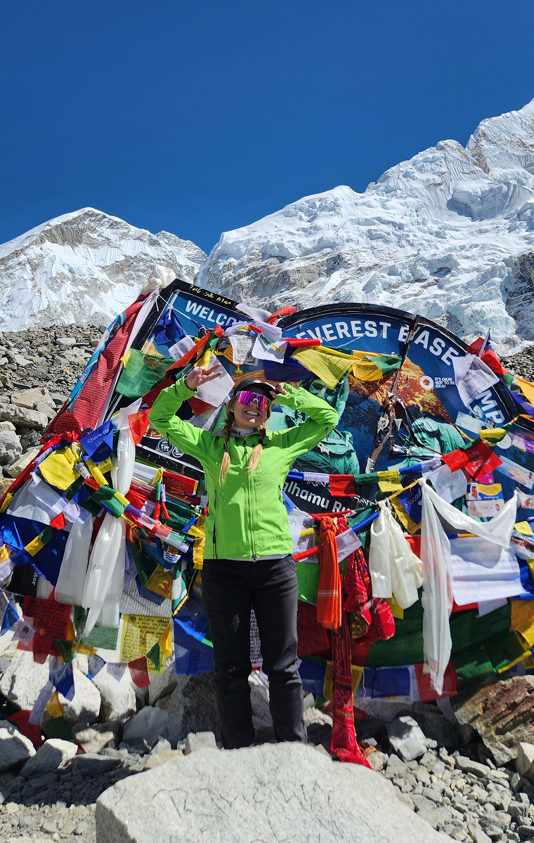 Girl smiling in front of Everest Base Camp sign in Nepal